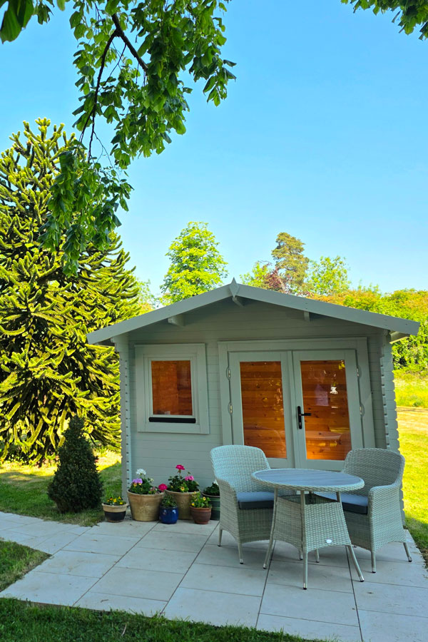 Summer-House White wooden summer house with patio furniture and flowers in-front